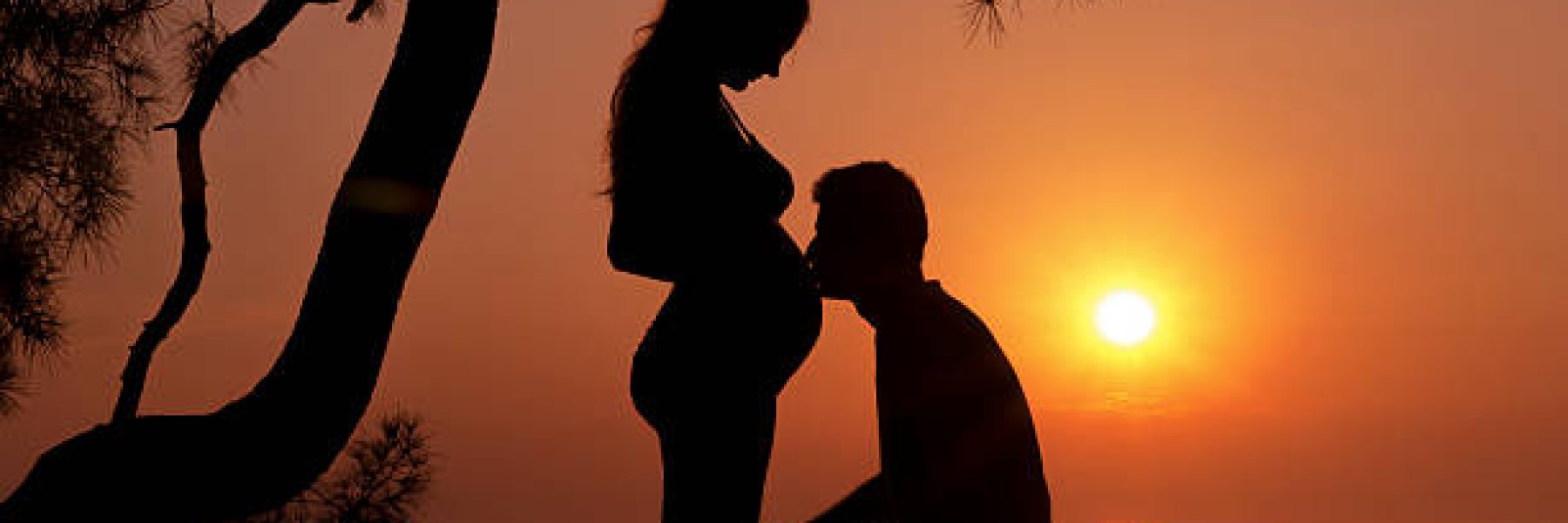 Young man kissing the belly of his pregnant women.